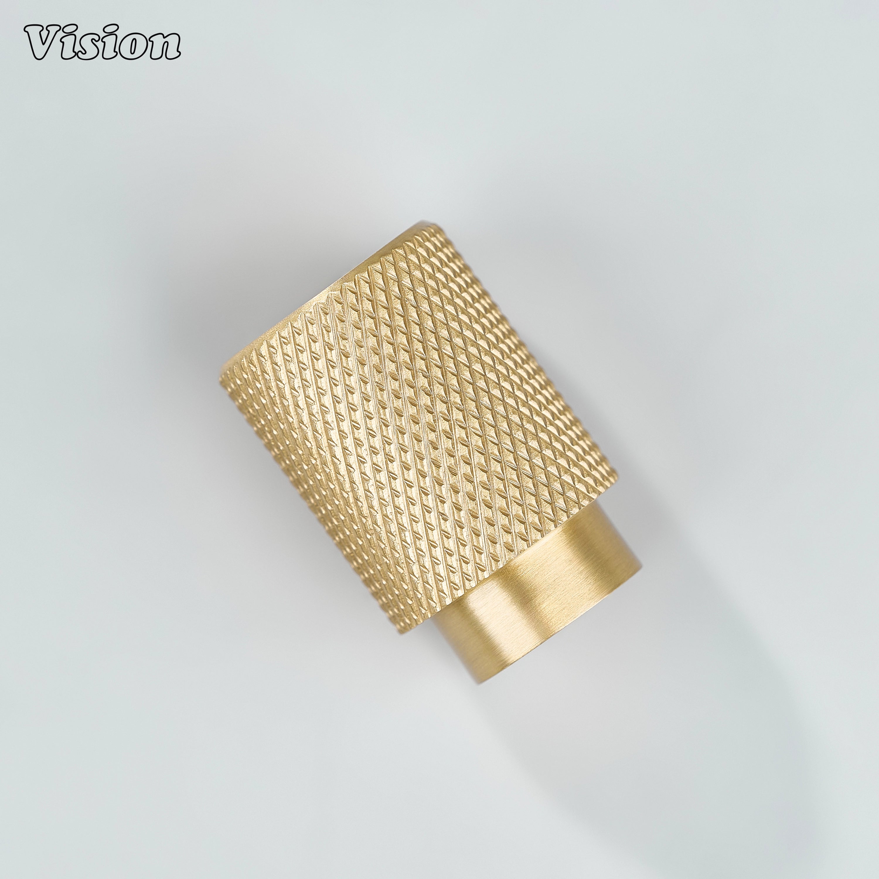 Modern gold knurled cylinder knob used for furniture drawers.