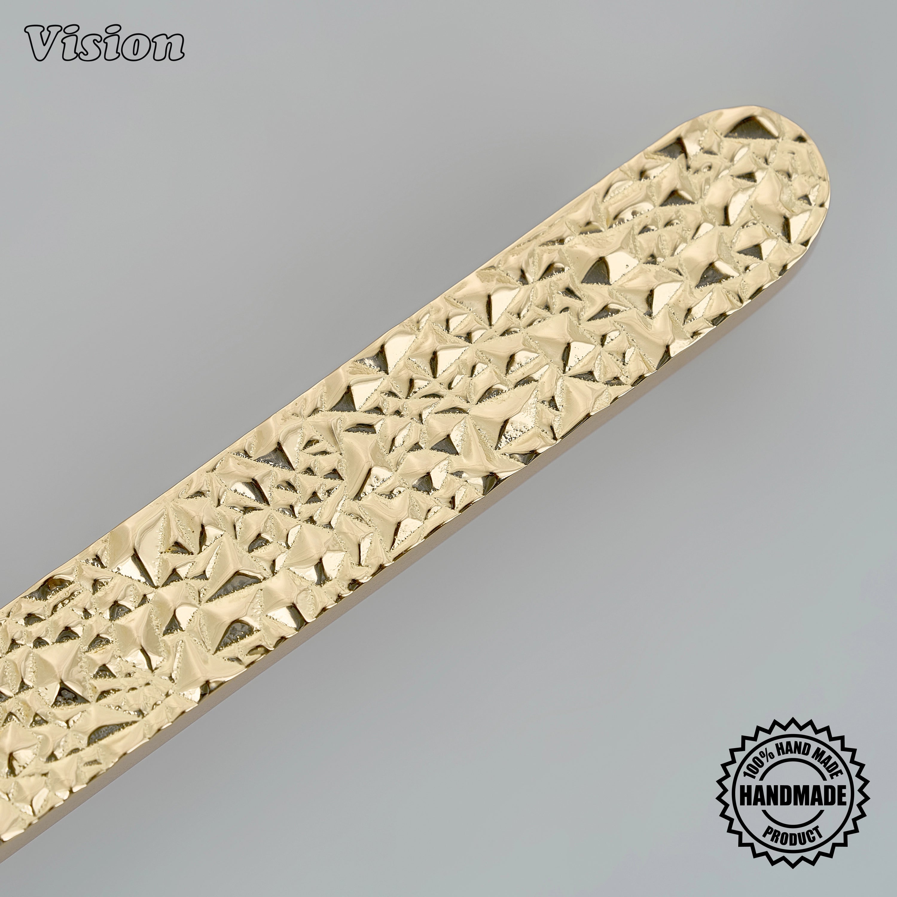 Handcrafted polished brass drawer handle with organic stone relief on oversized furniture doors