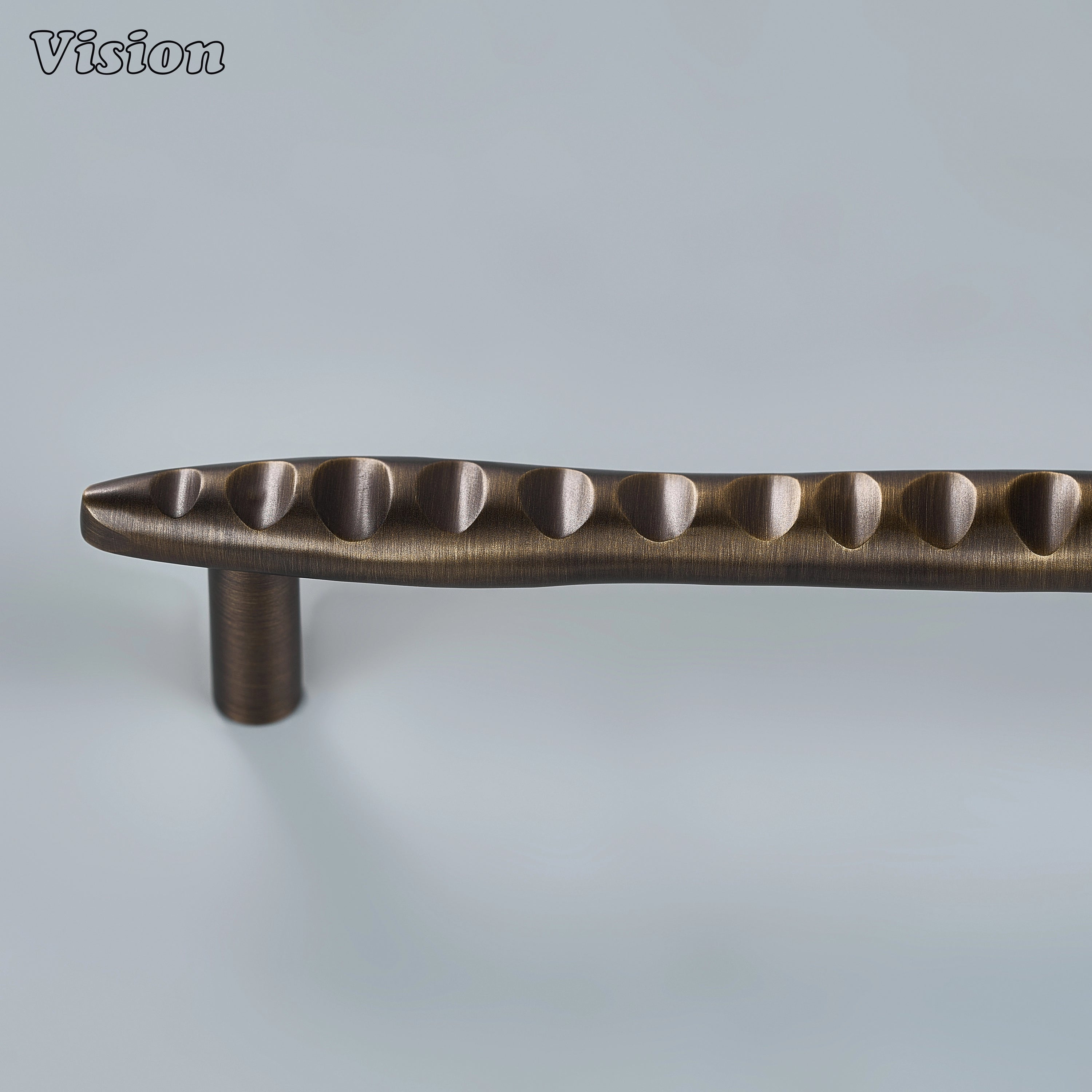 Textured antique bronze sculpted drawer pull with undulating ridges on custom kitchen cabinetry